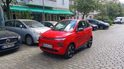 Rotes Microcar fährt durch Stadt.