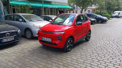 Rotes Microcar fährt durch Stadt.