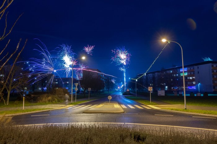 Silvesternacht auf einer Straßenkreuzung mit Böllern und Raketen.