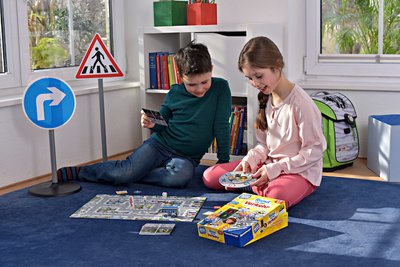 Zwei Kinder sitzen auf dem Boden und spielen mit Spielzeug-Verkehrsschildern.