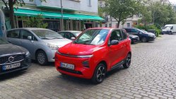 Rotes Microcar fährt durch Stadt.