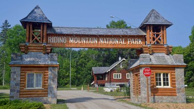 Großes Eingangstor aus Stein und Holz mit der Beschriftung Riding Mountain National Park.