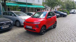 Rotes Microcar fährt durch Stadt.