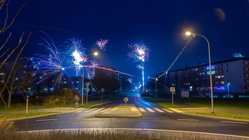 Silvesternacht auf einer Straßenkreuzung mit Böllern und Raketen.